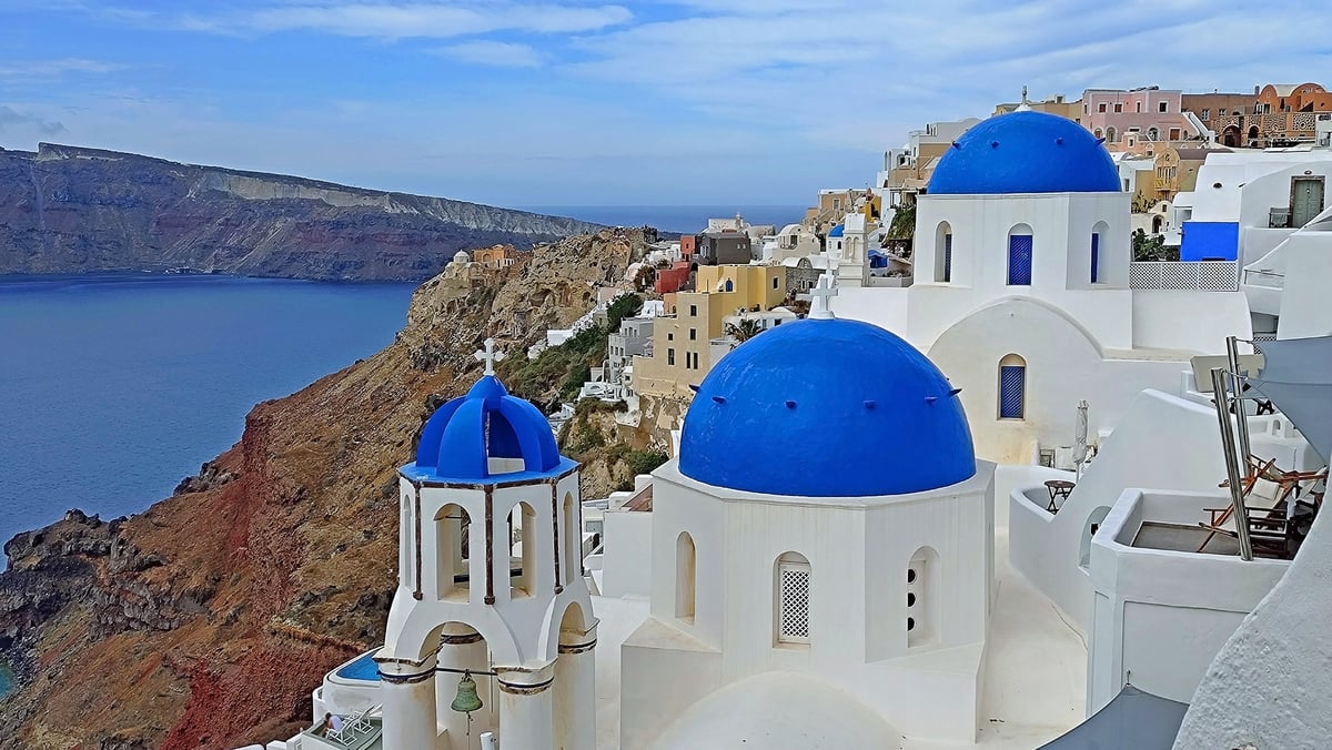 View of three blue domes in Oia, Santorini with blue sea and sky in the background